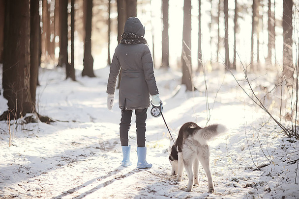 children play with a dog in the winter landscape of a sunny forest, snowfall girls and husky - Foto, immagini