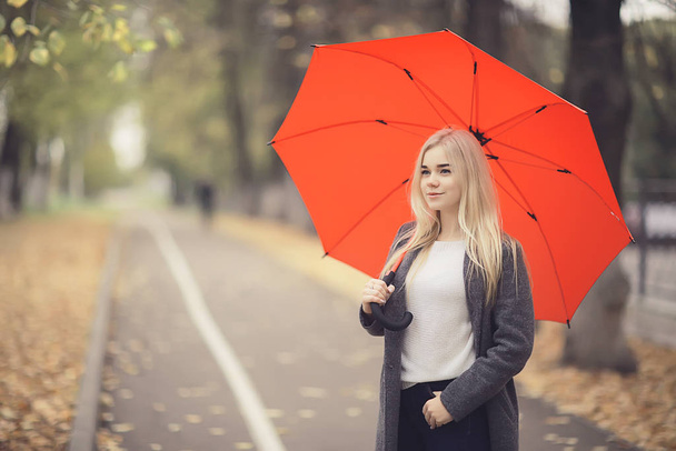 girl with umbrella posing in autumn park, october landscape lonely woman holding a red umbrella - Foto, Bild