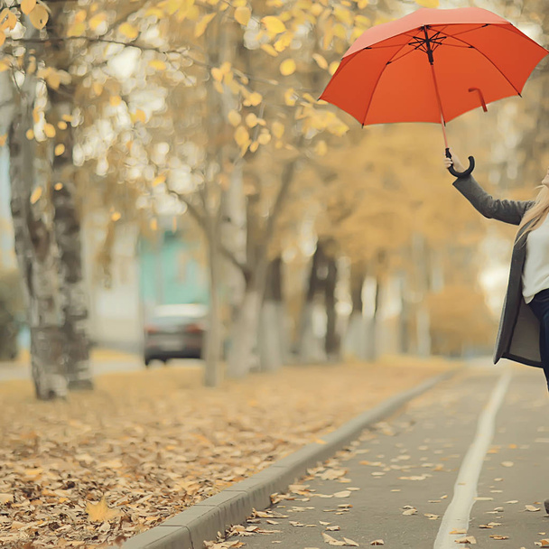 girl with a red umbrella, flying on an umbrella, jumping and having fun in a yellow autumn landscape - Φωτογραφία, εικόνα