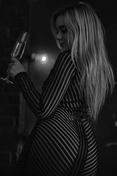 sexy blonde girl drinks champagne from a glass, evening glamorous style portrait - Фото, зображення