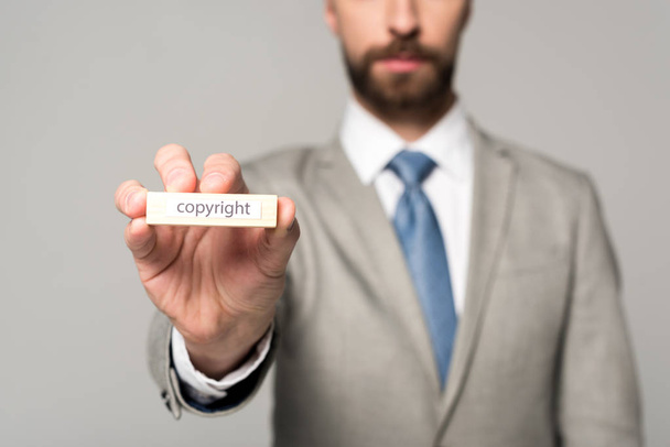 partial view of businessman showing wooden block with word copyright isolated on grey - Fotografie, Obrázek