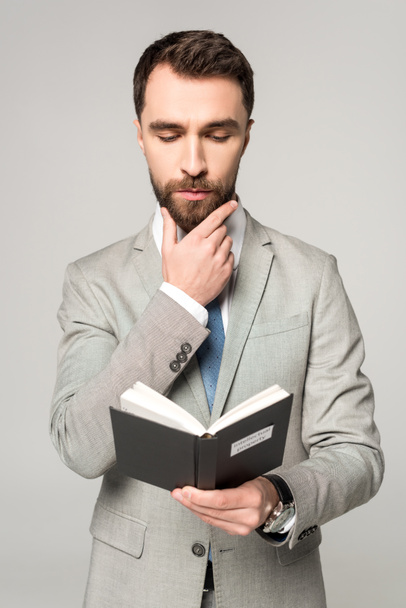 aufmerksamer Geschäftsmann liest Buch mit geistigem Eigentum Titel isoliert auf grau - Foto, Bild