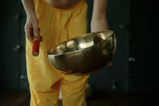 Tibetan singing bowl, a monk in yellow pants meditates and plays the musical bowl, Buddhism, religion - Photo, image