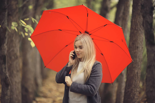 chica con paraguas posando en el parque de otoño, paisaje de octubre mujer solitaria sosteniendo un paraguas rojo
 - Foto, Imagen