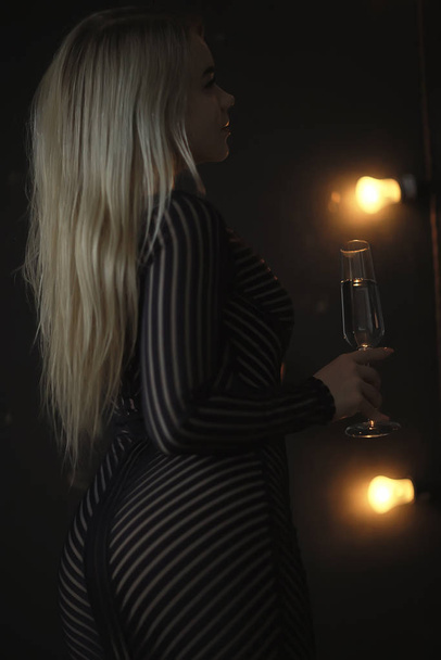 Seksi sarışın kız kadehten şampanya içiyor. Akşam gösterişli bir portreden. - Fotoğraf, Görsel