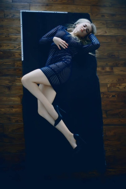 sexy model is lying on the wooden floor of parquet, a beautiful adult model in posing in an erotic dress - Фото, зображення
