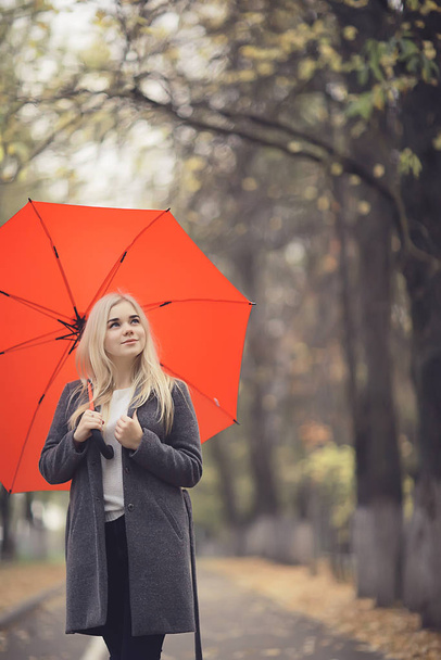 girl with umbrella posing in autumn park, october landscape lonely woman holding a red umbrella - Foto, afbeelding