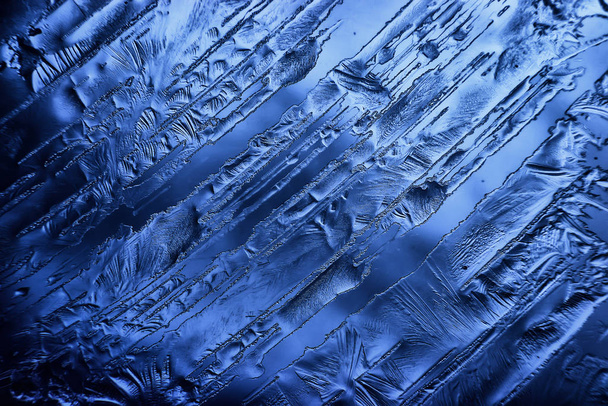blauw ijsglas achtergrond, abstracte textuur van het oppervlak van het ijs op het glas, bevroren seizoensgebonden water - Foto, afbeelding