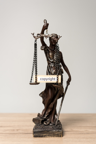 themis Statue und Holzblock mit Wort copyright auf Schuppen auf Holztisch isoliert auf grau - Foto, Bild