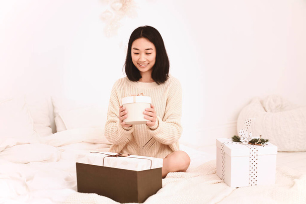 Woman holds box with ribbon sitting on bed - Foto, Bild