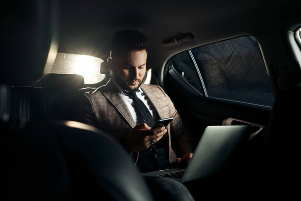 kaveri autossa kannettavan tietokoneen ja puhelimen kanssa
 - Valokuva, kuva