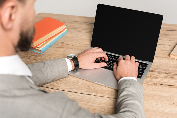 cropped view of businessman using laptop with blank screen isolated on grey - Foto, Bild