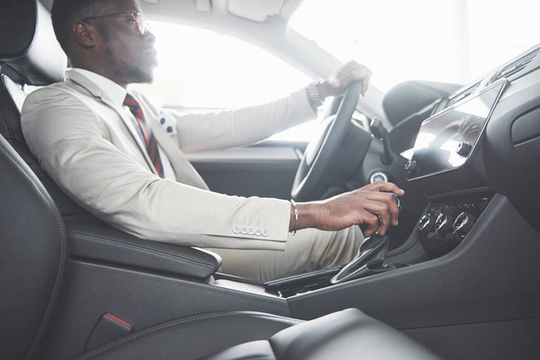 Stylish black businessman sitting behind the wheel of new luxury car. Rich african american man. - Foto, Bild