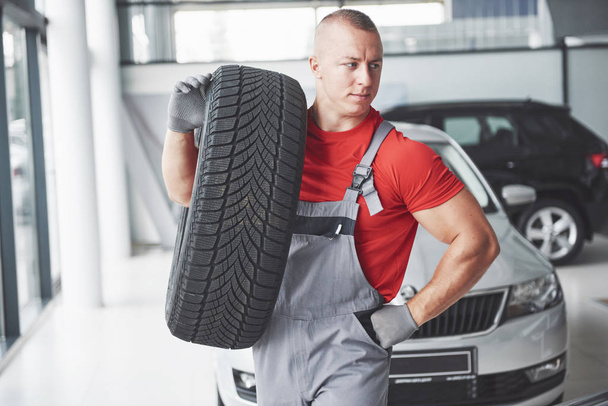 Mechanic holding a tire tire at the repair garage. replacement of winter and summer tires - 写真・画像
