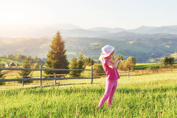 Cute happy little baby girl play outdoors in the lawn and admiring mountains view. Copy space for your text. - Photo, Image
