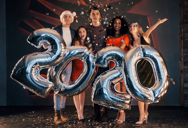 Grupa zabawnych młodych, pięknych wielonarodowych ludzi rzucających konfetti na imprezę. Szczęśliwego Nowego Roku - Zdjęcie, obraz