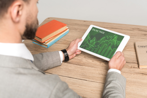 Ausgeschnittene Ansicht eines Geschäftsmannes mit digitalem Tablet und Online-Handel-App auf dem Bildschirm isoliert auf grau - Foto, Bild