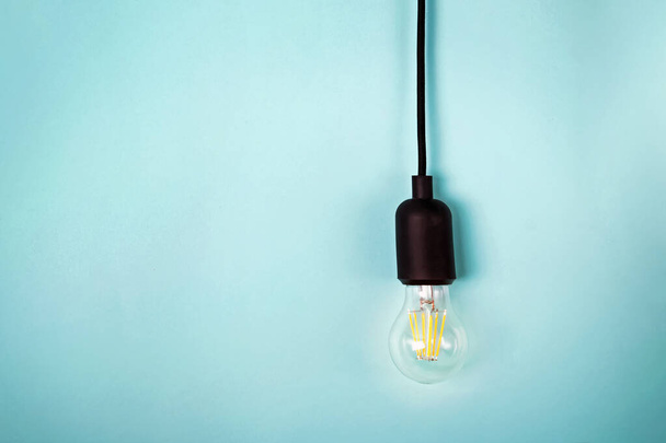 Ampoule électrique rétro avec cordon isolé sur fond couleur turquoise avec espace de copie
. - Photo, image