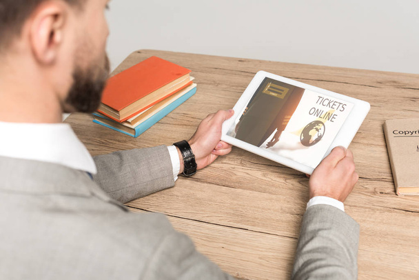 vista recortada de hombre de negocios utilizando tableta digital con tickets aplicación en línea en la pantalla aislada en gris
 - Foto, Imagen