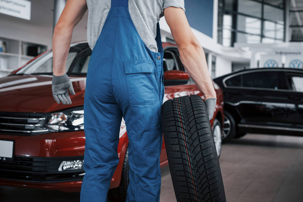 Mechanic holding a tire tire at the repair garage. replacement of winter and summer tires. - Foto, Imagem