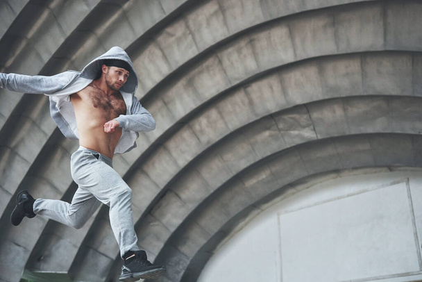 A young man is jumping. Parkour in urban space, sporting activity - Φωτογραφία, εικόνα