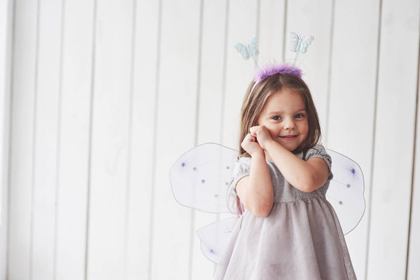 Shy and holding hands to the face. Beautiful little girl with fairy costume having fun posing for the pictures. - Photo, Image
