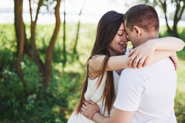 Happy and young pregnant couple hugging in nature. - Fotó, kép