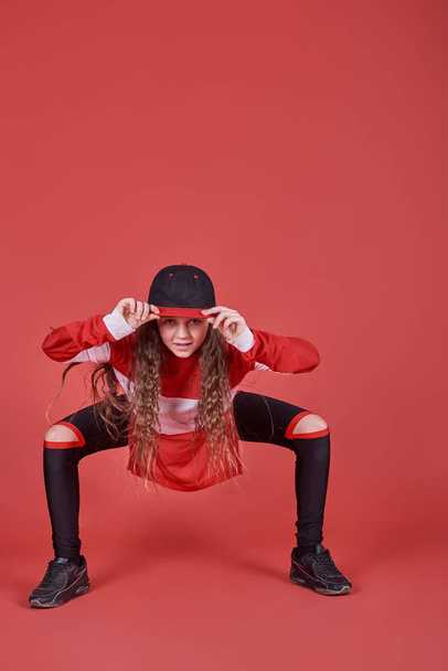 Young urban woman dancing on red background, modern slim hip-hop style teenage girl. - Foto, imagen