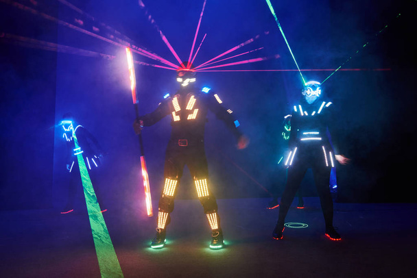 Laser show performance, dancers in led suits with LED lamp, very beautiful night club performance, party. - Foto, imagen