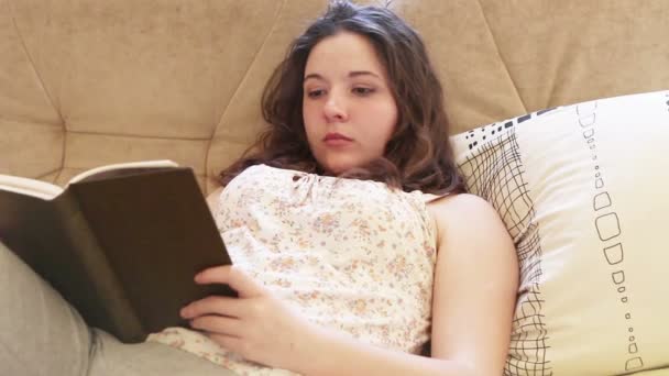 Girl reads bestseller book on comfy sofa - Materiaali, video