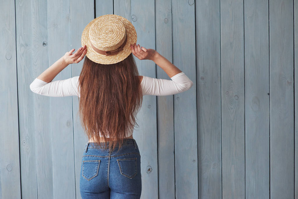 Style conception. Girl in the hat turned her back to the camera. Standing at the wooden background. - Foto, imagen