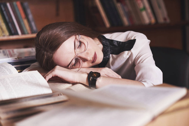 Nuori tyttö opiskelija on väsynyt lukusalissa vanhan kirjaston
. - Valokuva, kuva