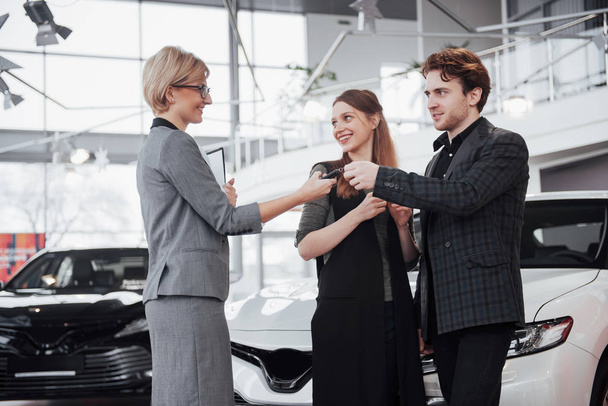 Now her dream comes true. Car salesman giving the key of the new car to the young attractive owners. - Valokuva, kuva
