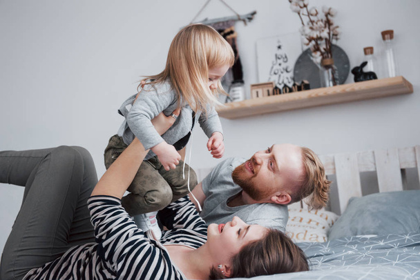 Happy family together. Mother, father and child daughter hugging in bedroom in festive day. - Fotografie, Obrázek