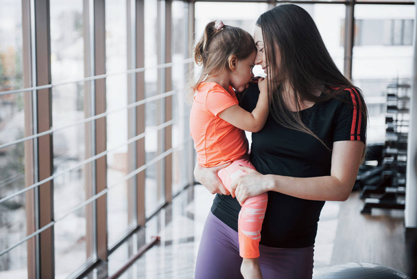 Mother holds her daughter in her arms in the gym - Foto, imagen