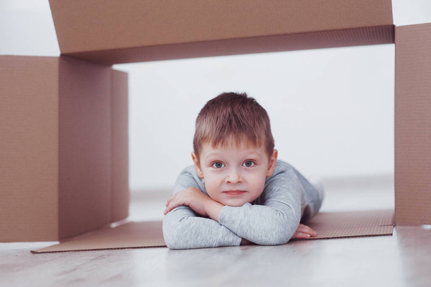 Child preschooler boy playing inside paper box. Childhood, repairs and new house concept. - Φωτογραφία, εικόνα