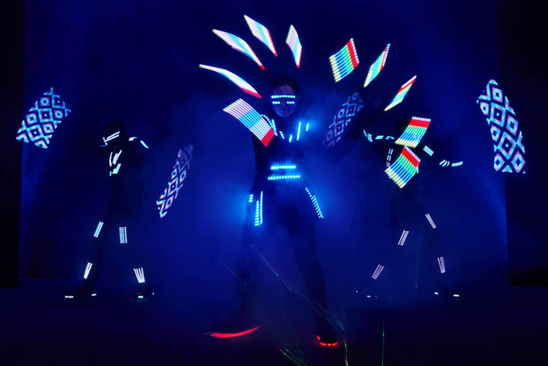 Laser show performance, dancers in led suits with LED lamp, very beautiful night club performance, party. - Foto, afbeelding