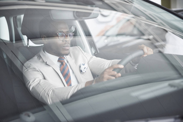 edessä näkymä Komea afrikkalainen tyylikäs vakava liikemies ajaa autoa
. - Valokuva, kuva