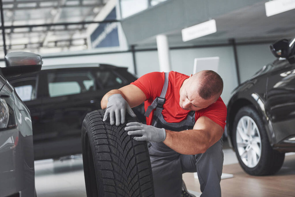 Mechanic holding a tire tire at the repair garage. replacement of winter and summer tires. - Foto, imagen