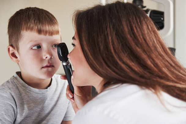 Boy have eye test with special little device. Concentrating on sight health. - Photo, image