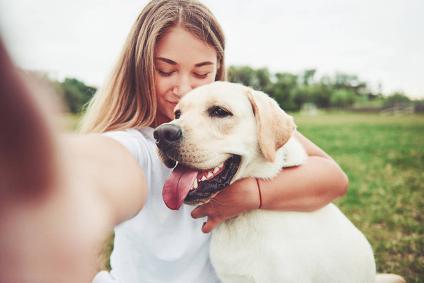 Attractive young woman with labrador outdoors. Woman on a green grass with dog labrador retriever. - Fotografie, Obrázek