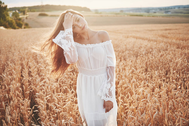 Happy young girl in a wheat field under sunlight - Фото, изображение
