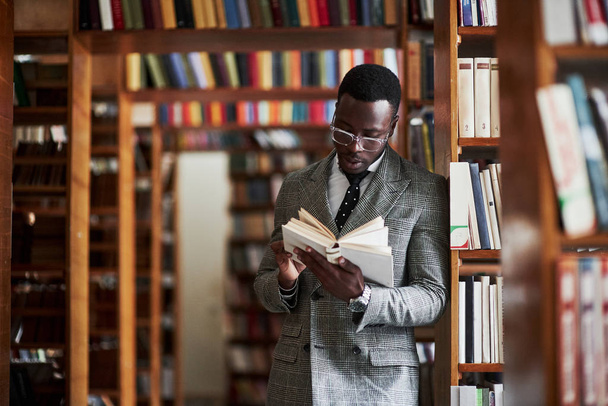 An African American man in a business suit standing in a library in the reading room - Foto, Imagen