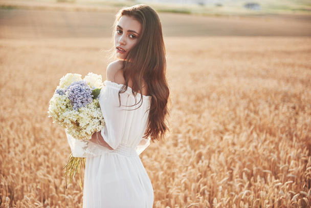 Beautiful girl in white dress running on the autumn field of wheat at sunset time - Foto, Bild