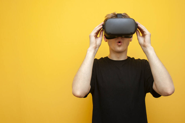 yllättynyt nuori kaveri, jolla on VR-lasit keltaisella taustalla, katsoo kauhua ja huutaa, mies käyttää virtuaalitodellisuuslaseja ja pelkää
 - Valokuva, kuva