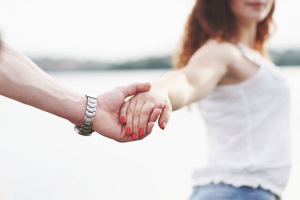 Beautiful girl holding her boyfriend's hand. Summer season - Фото, зображення