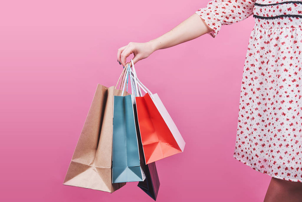 Close-up of Female hand holding colorful shopping bags on pink background. - Foto, Imagem