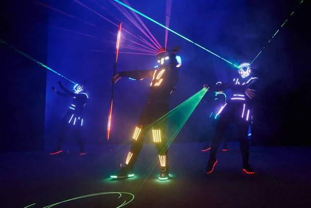 Laser show performance, dancers in led suits with LED lamp, very beautiful night club performance, party. - Фото, зображення