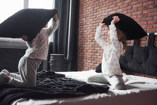 Naughty children Little boy and girl staged a pillow fight on the bed in the bedroom. They like that kind of game. - Fotoğraf, Görsel