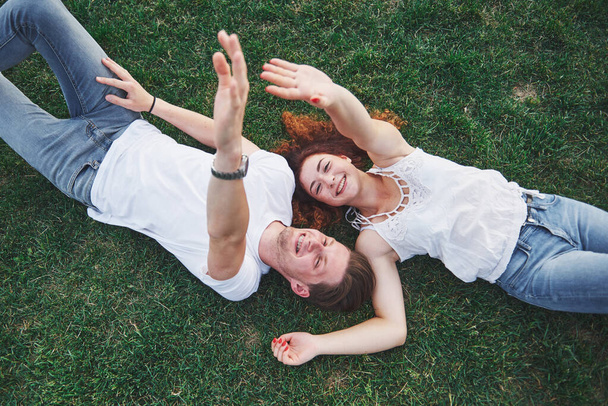 A romantic couple of young people lying on the grass in the park. Top view. - Foto, imagen
